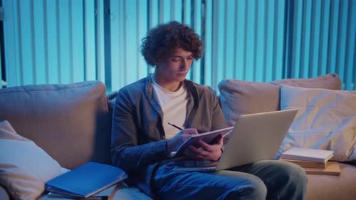 Man Studies with Laptop and Notebook Remote Learning Night Focus Neon Mood
