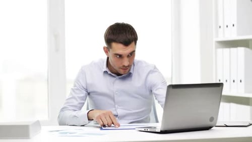 Busy hispanic businessman working with laptop and paperwork at the office
