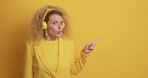 Woman smiles and points on a yellow background