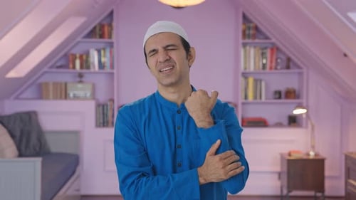 Man Rubs Sore Wrist in Bedroom Setting