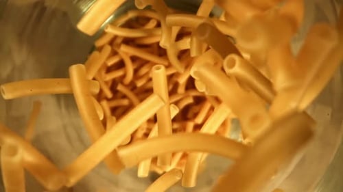 Macaroni Noodles Falling Into a Stainless Steel Bowl