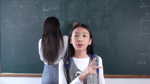 Girl Explains Math with Teacher in Classroom