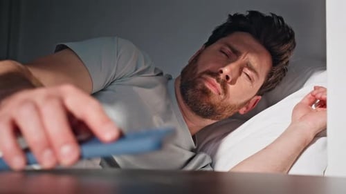 Man Waking Up and Reaching for Phone in Bed