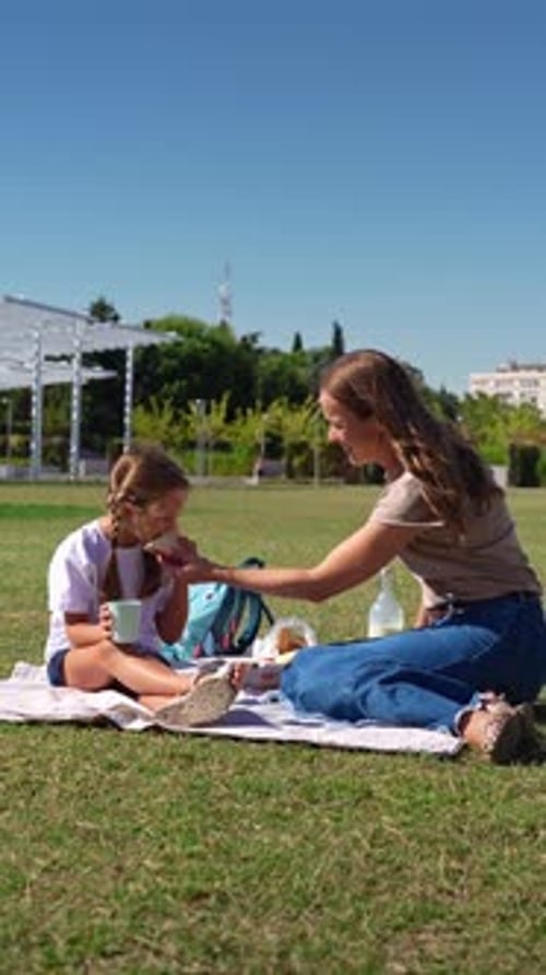 Mother and Daughter Having a Happy Picnic Lunch in the Park