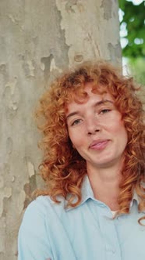 Jeune femme rousse posant près d'un arbre