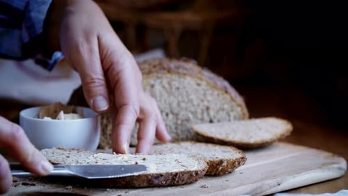 Spreading Creamy Herb Butter on a Slice of Rustic Bread
