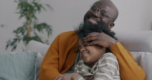 Father and Child Embracing on Sofa Smiling