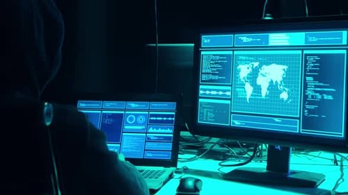 Man in Hood Coding at Computer in Dark Room