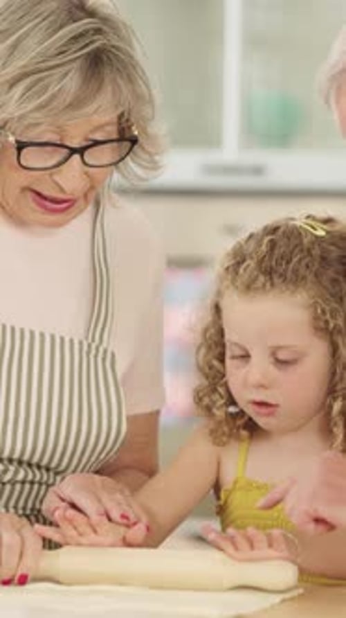 Grandmother and Granddaughter Rolling Dough in Kitchen
