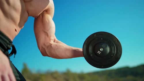 Muscular Man Lifting Dumbbell in Outdoor Setting
