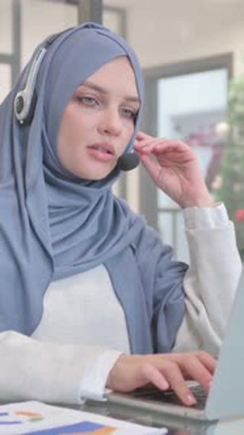 Woman in Hijab with Headset Talking Online in Call Center, vertical video