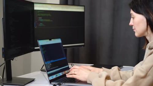 Female programmer writes code on laptop in office