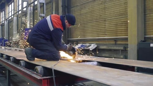 Schlosser schneidet Stahlträger mit Winkelschleifer in der Fabrik
