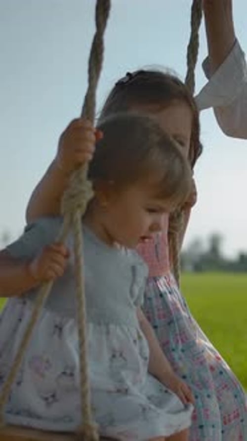 Mother Pushing Children on Tree Swing