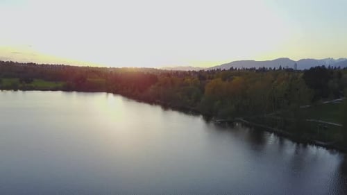 Aerial Footage of a Lake in the City Park During a Colorful and Vibrant Sunset with Red Color Sky