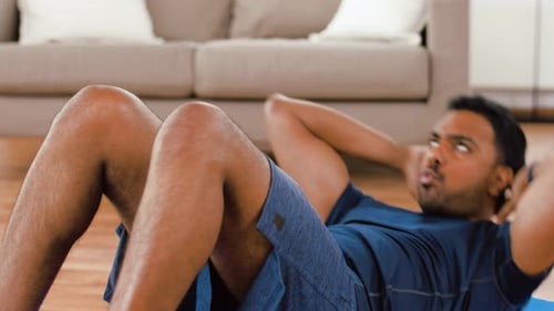 Man doing sit-ups at home on exercise mat