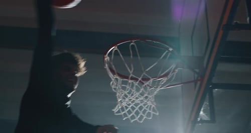 Ralenti cinématographique d'un jeune joueur professionnel en train de faire un slam dunk pendant une basse