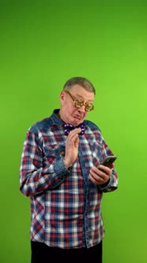 Man Looks at Smartphone and Taps the Screen