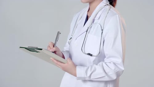 Female Doctor Writing on Clipboard in Studio Setting