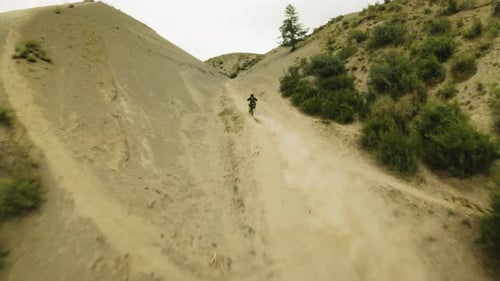 Dirt Biker Riding Down a Desert Hillside Trail