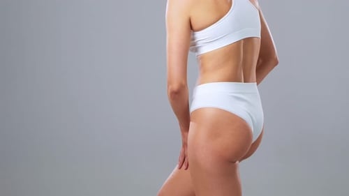 Junge, fitte und schöne Frau im weißen Badeanzug posiert auf grauem Hintergrund, Gesundheitswesen, Diät, Sport
