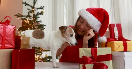 Woman Petting Dog Surrounded by Christmas Gifts