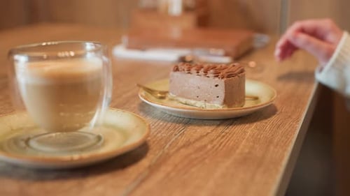 Chocolate Cake on Table As Attendant Serves Hot Drink in Cozy Cafe