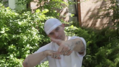 Street dancer performs a dance, making expressive movements with tattooed hands.