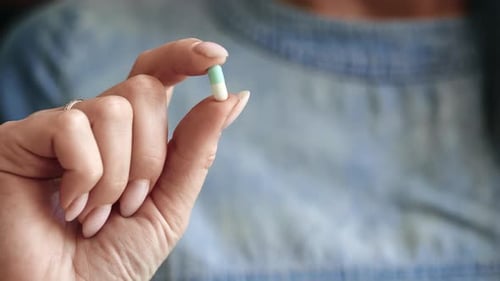 Adult Holding a White and Green Capsule