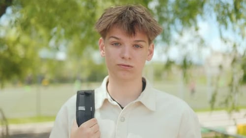 Teen with backpack looking at the camera outdoors
