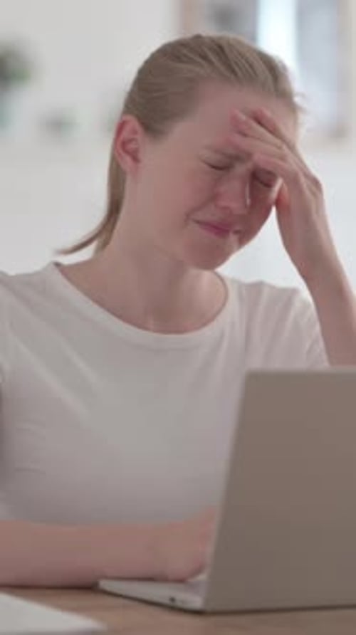 Blonde Woman with Headache Sitting near a Laptop