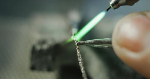Slow motion macro close up of goldsmith working on a handmade jewelry bracelet chain of precious m