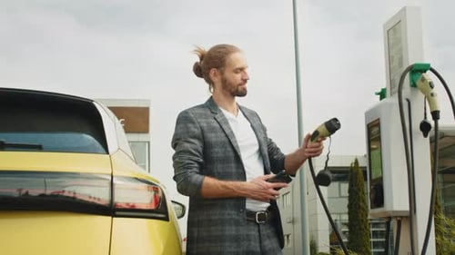 Caucasian Young Man Charging Electric Car at a Public Charging Station