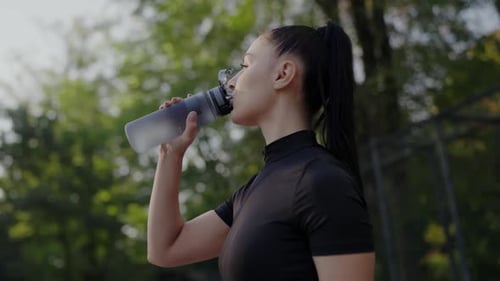 Woman Drinking Water from Bottle After Exercise