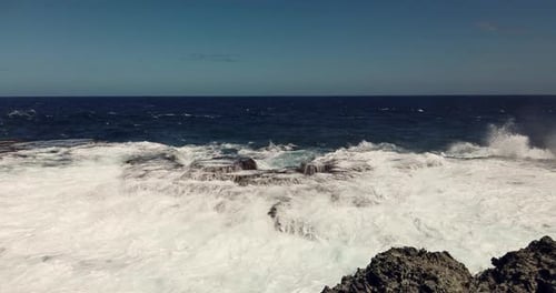 Foto aérea das ondas do mar batendo nos penhascos rochosos de uma ilha deserta antes da tempestade.