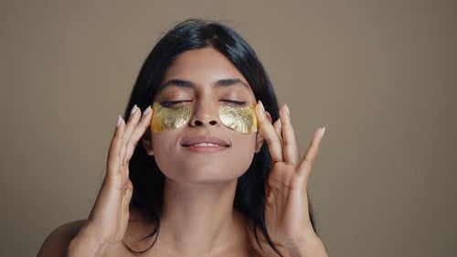 Radiant Woman Applies Gold Eye Patches