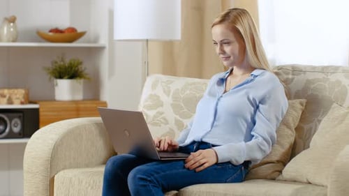 Young Woman Using Laptop on Couch at Home