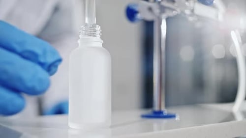 Scientist Filling a Glass Bottle in a Lab