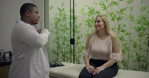 Woman Sitting on Exam Table Talking to Doctor