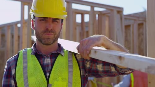 Construction worker carries lumber at a construction site