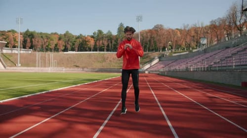 Hübscher bärtiger, sportlicher Typ, der sich auf das Laufen vorbereitet, dynamische Sprünge macht und aerobes Cardio-Aufwärmen macht