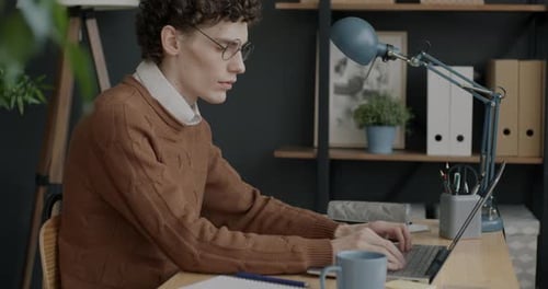 Young Adult Typing on Laptop in Home Office