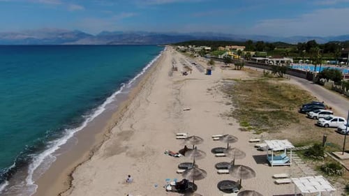 Aerial Drone Flies Over Long Sandy Beach with Sunbeds, Umbrellas, and Beach Bars.