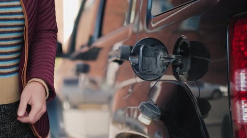 A Woman is Running Her Black Car Opens the Hatch and Inserts the Pistol for Refueling