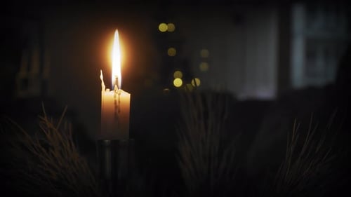 Eine einzelne brennende Kerze in einer gemütlichen, warmen Umgebung zur Weihnachtszeit.