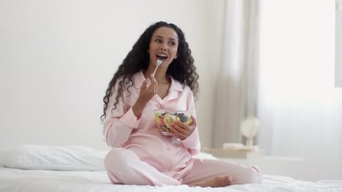 Pregnant Woman Enjoys Fruit Bowl in Bedroom