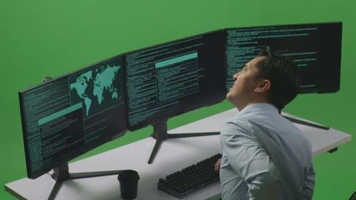 Asian Man Developer Having Backache While Write Code With Multiple Computer Screens In Green Screen