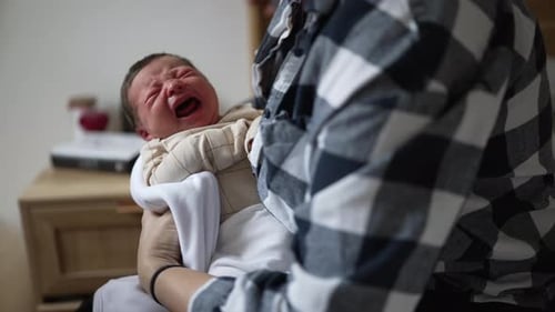 Infant Cries While Being Held by Adult Indoors