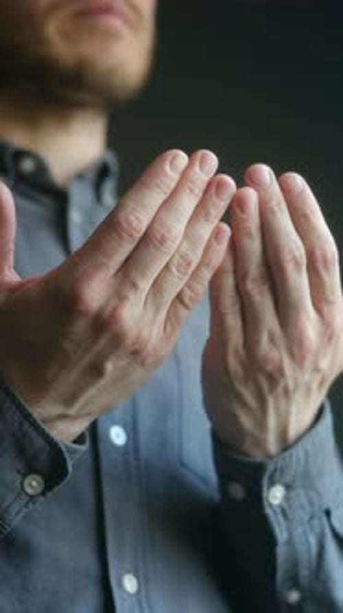 Man with Hands Raised in Prayer, Dark Background
