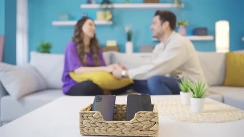 Young Couple Holding Hands on Sofa at Home